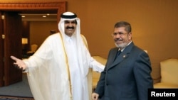 Qatar's Emir Sheikh Hamad bin Khalifa al-Thani (L) greets Egypt's President Mohamed Mursi during the Arab League summit in Doha, March 26, 2013. 