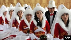 FILE - Kyrgyz brides and bridegrooms pray in the central mosque during a mass wedding ceremony in the capital Bishkek, Oct. 30, 2013. Fifty couples took part in the mass wedding ceremony sponsored by a state company.