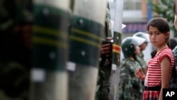 烏魯木齊的一個維吾爾族小女孩被中國武警擋住去路。