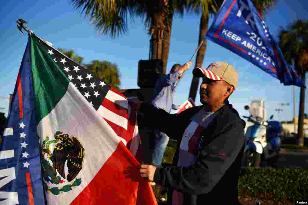 José Casares, de 32 años, agita banderas en apoyo de Trump mientras algunos votantes se alinean en un colegio electoral durante el día de las elecciones en Houston, Texas.