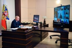 President Vladimir Putin meets with his cabinet at the Novo-Ogaryovo residence, Aug. 11, 2020. Putin says that a coronavirus vaccine developed in the country has been registered for use and one of his daughters has already been inoculated.