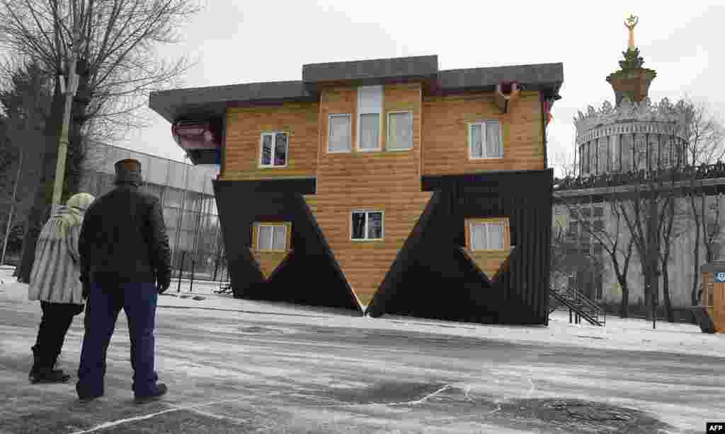 Pengunjung melihat sebuah "rumah terbalik" dalam pameran di Moskow, Rusia.