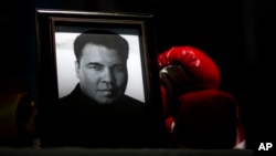 FILE - A portrait of Muhammad Ali is displayed next to a pair of boxing gloves at the I Am Ali Festival in Louisville, Kentucky, June 8, 2016.