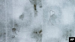 Archivo - Huellas crean la forma de un corazón en un campo de rugby cubierto de nieve en Santiago de Chile, miércoles 8 de mayo de 2024. 
