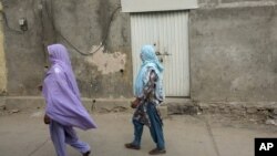 Local women walk past locked house of Christian girl in a suburb of Islamabad, Aug. 20, 2012.