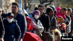 FILE - Migrants queue on a bridge crossing the border river Inn at the German-Austrian frontier between Braunau and Simbach am Inn near Passau, Germany, Nov. 1, 2015. 