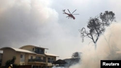 A fire-bombing helicopter works to contain a bushfire along Old Bar road in Old Bar, New South Wales, Australia, Nov. 9, 2019.