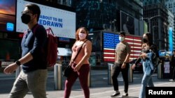 FILE - People with masks to protect against the coronavirus walk in Times Square, in New York City, July 23, 2021.