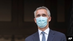 Sekretaris Jenderal NATO Jens Stoltenberg, mengenakan masker wajah berdiri di samping Perdana Menteri Yunani Kyriakos Mitsotakis sebelum pertemuan mereka di Athena pada Selasa, 6 Oktober 2020. (Foto: AP/Petros Giannakouris)