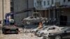 Pegawai dinas kota memindahkan mobil yang hancur dari tempat parkir di sebelah gedung apartemen yang rusak berat selama serangan drone Rusia besar-besaran, di tengah serangan Rusia terhadap Ukraina, di Kyiv, Ukraina 30 Mei 2023. (Foto: REUTERS/Alina Smutko)