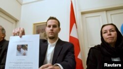 FILE - Christine Levinson, right, wife of former FBI agent Robert Levinson, watches as her son Daniel displays a printout of his father's picture to journalists during a news conference at Switzerland's embassy in Tehran, Dec. 22, 2007. 