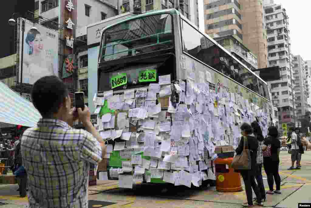 A man takes picture of a bus covered with messages of support at Mongkok shopping district after thousand of protesters blocked the road in Hong Kong, Sept. 30, 2014.