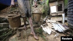 Un hombre saca lodo de una casa en una ladera en Scorpion Alley, Carenage, a unos 10 kilómetros de Puerto Príncipe, Haití, donde las lluvias torrenciales de Isaac han causado algunos daños materiales.