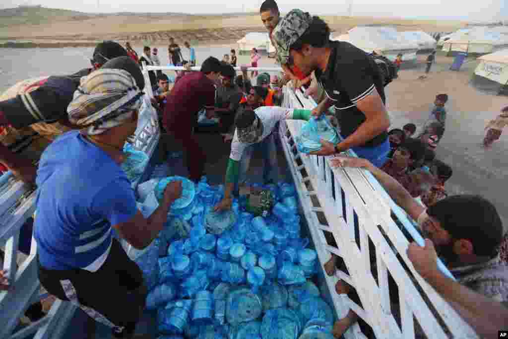 Pengungsi irak berkumpul di sekitar truk makanan untuk mendapatkan hidangan berbuka puasa dalam hari pertama Ramadan di kamp Khazer, di luar kota Irbil, Irak utara (29/6). (AP/Hussein Malla)