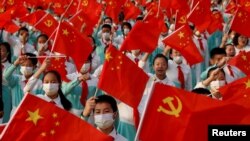 表演者在 2021年7月1日在中國北京天安門廣場慶祝中國共產黨成立100週年的活動彩排時揮舞著國旗和黨旗。