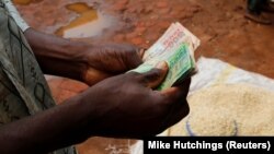 Un commerçant malawite compte son argent alors qu'il vend du maïs près de la capitale Lilongwe, au Malawi, le 1er février 2016.