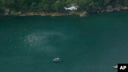 In this image made from a video, a search and rescue helicopter flies above search boats in Hawkesbury River, New South Wales, Australia, Dec. 31, 2017. A seaplane crashed into the river in Sydney.