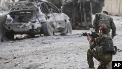 An Afghan soldier secures the scene of a suicide attack at the gate of an airport in Jalalabad, Nangarhar province east of Kabul, Afghanistan, Feb. 27, 2012.