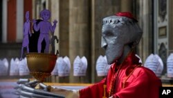 Una escultura que representa a un sacerdote católico y un cáliz lleno de figuras de niños, durante una protesta afuera de la Catedral Metropolitana en La Paz, Bolivia, jueves 16 de mayo de 2024. 