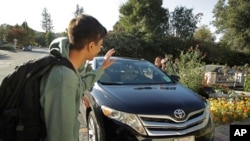 Zum driver Stacey Patrick, right, waves goodbye to student Saahas Kohli, left, as he returns home from school in Saratoga, California, Oct. 29, 2019.