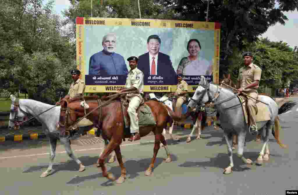 Patrol police pass a billboard with images of India's Prime Minister Narendra Modi, China's President Xi Jinping and Anandiben Patel, Chief Minister of the western Indian state of Gujarat, ahead of their arrival in Ahmedabad, Sept. 16, 2014.