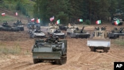 Kendaraan militer dan tank milik Polandia, Italia, Kanada dan Amerika Serikat berpartisipasi dalam latihan militer NATO Kadaga, Latvia, pada 13 September 2021. (Foto: AP/Roman Koksarov)