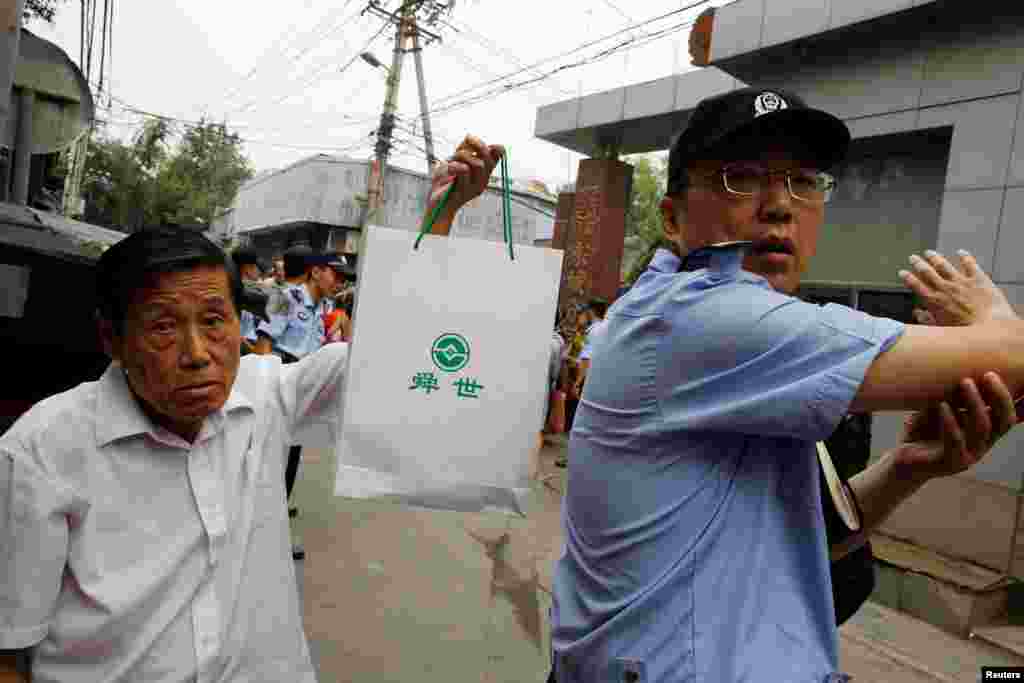 2018年8月27日,P2P投资计划的受害人在北京东城区公安分局前面请愿,一名男子拿着带有P2P贷方徽标的袋子。