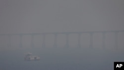 FILE - A boat navigates the Negro River amid smoke from wildfires in Manaus, Amazonas state, Brazil, Aug. 27, 2024.