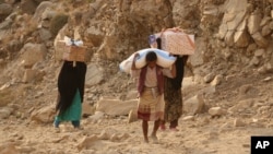 FILE - Yemenis carry relief supplies as they walk along a path outside the city of Taiz, Yemen, Jan. 17, 2016.