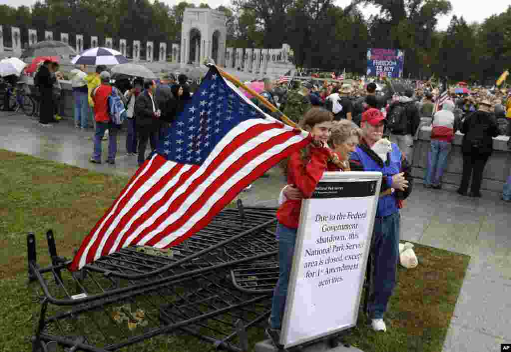 Kaylee, Sherry and Michael Cantrell pose for a photo with a sign and removed barricades at the World War II Memorial in Washington, Oct. 13, 2013.