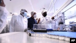 FILE - South African President Cyril Ramaphosa, right, heads a government delegation on a visit to ASPEN Pharmaceuticals in Port Elizabeth, South Africa, March 29, 2021. The company Aspen has begun production of COVID-19 vaccine for African countries.