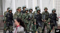 Polisi paramiliter dengan perisai dan tongkat berpatroli dekat alun-alun di Urumqi, China (23/5).