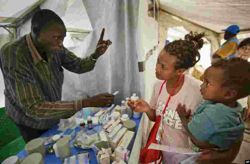 Yared, 2, is held by his mother, Madhn, who fled from the town of Bor a few days ago. She receives medicine for her child at a Medecins Sans Frontieres (MSF) medical tent, at a United Nations compound, Juba, South Sudan, Dec. 31, 2013.