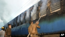 An Indian fire official douses fire coming out from a coach of a passenger train at Nellor nearly 500 kilometers (310 miles) south of Hyderabad, India, Monday, July 30, 2012.