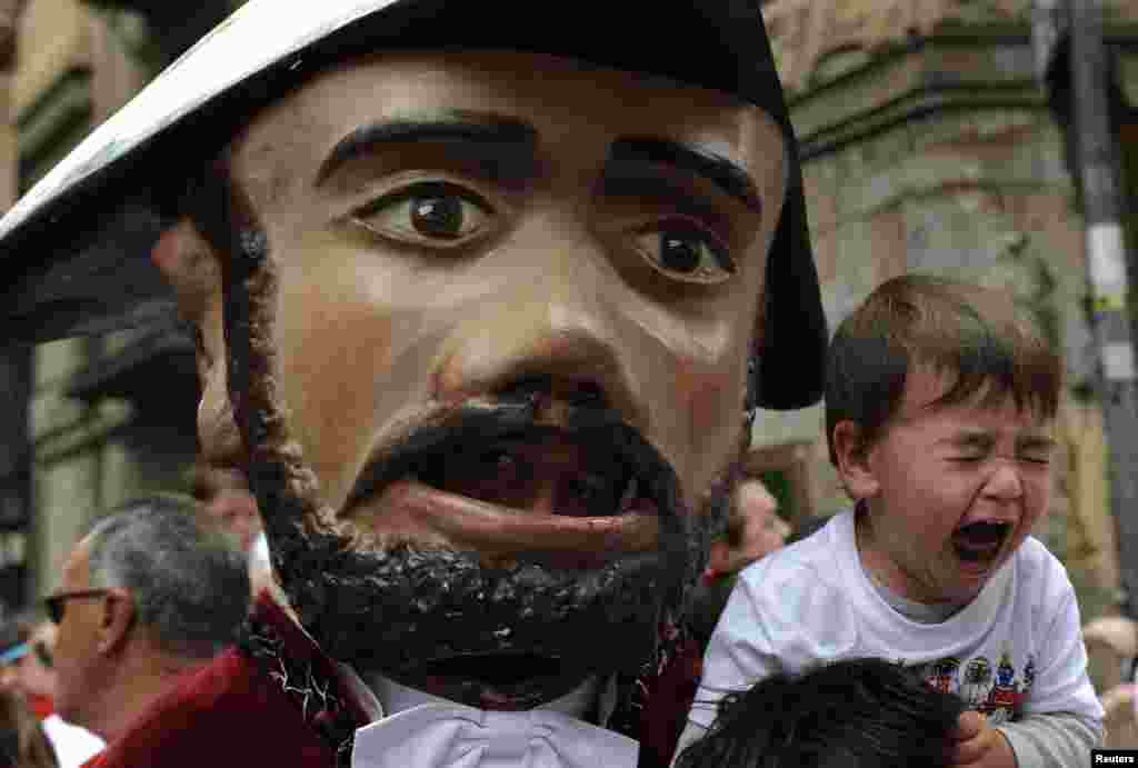 A child cries next to a "Kiliki" during the San Fermin festival's Comparsa de gigantes y cabezudos (Parade of the giants and the big heads) in Pamplona, Spain.