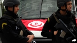 Le drapeau tunisien sur le capot d'un véhicule derrière des policiers qui montent la garde sur le lieu d'une fusillade, Tunis, Tunisie, 20 mars 2015. (AP Photo/Christophe Ena)