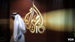 FILE- In this Wednesday Nov. 1, 2006, file photo, a Qatari employee of Al-Jazeera Arabic language TV news channel walks past the logo of Al-Jazeera in Doha, Qatar.