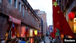 台湾金门一条街道商店旁插有中国和台湾的旗帜。（2018年8月19日）