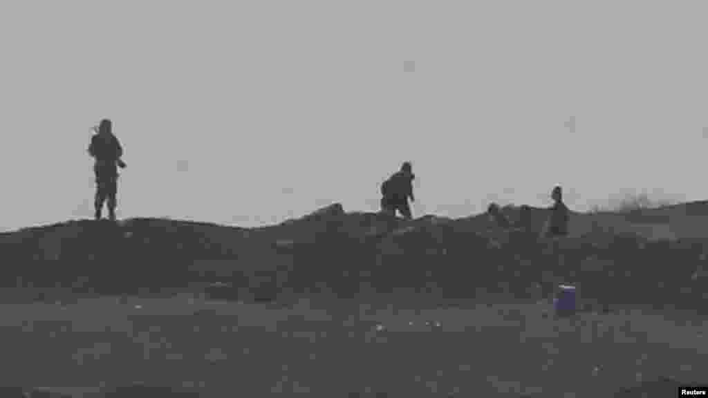Des hommes armés, présumés être des combattants de l’Etat Islamiques par des sources locales, pris en photo au contrôle de passage à l’Ouest de la ville de Kobani, près de Mursitpinar à la frontière Turco-Syrienne, le 13 ocotbre 2014. REUTERS/Umit Bektas