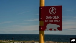 A young man watches for potential polar bears while walking near the Hudson Bay, Aug. 3, 2024, in Churchill, Manitoba. 
