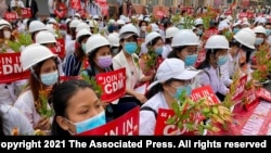 2021年2月21日在曼德勒舉行的反政變遊行中，醫學院學生戴著口罩，舉著標語牌聚集在一起。