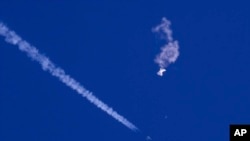 Balon mata-mata China setelah ditembak jatuh, terlihat melayang di atas Samudra Atlantik, tepat di lepas pantai South Carolina, di dekat awan putih jejak pesawat jet tempur AS, Sabtu, 4 Februari 2023.(Chad Fish via AP)