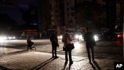 Ciudadanos de Caracas esperan un autobós en la oscuridad debido a un nuevo apagón el lunes, el cual desató el temor a que regresen los apagones.