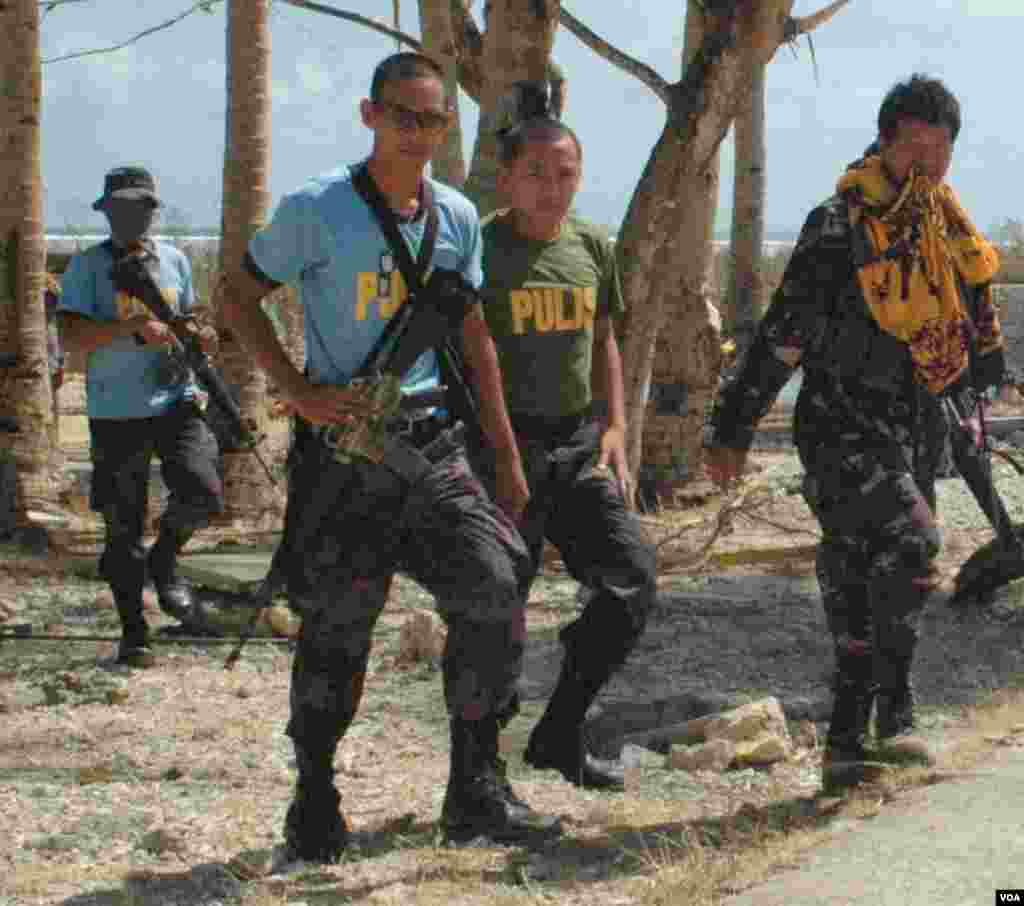 Police come to meet an incoming US Navy helicopter landing at Hernani, Philippines, Nov. 19, 2013. (Steve Herman/VOA)