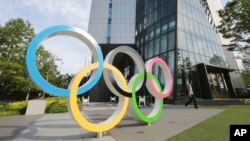 Seorang pria berjalan melewati cincin Olimpiade di Tokyo, Senin, 7 Juni 2021. (Foto: AP/Koji Sasahara)