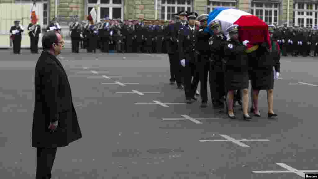 French President Francois Hollande looks at a coffin as he attends a national tribute at Paris Prefecture for the three officers killed during last week's attacks by Islamic militants, Jan. 13, 2015.