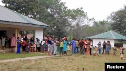 FILE - Cameroonian refugees stand outside a center in Agbokim Waterfalls village, which borders on Cameroon, in Nigeria, Dec. 9, 2017.
