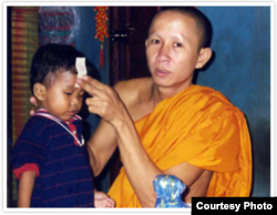 ព្រះសង្ឃ​ម្នាក់​កំពុង​ឲ្យពរជ័យដល់ Jordan Pisey Windle មុន​ពេល​ចេញ​ដំណើរ​មក​រស់នៅ​សហរដ្ឋ​អាមេរិក​ជាមួយ​នឹង​ឪពុក​ចិញ្ចឹម​របស់​ខ្លួន​គឺលោក Jerry Windle។ (រូបថត​ផ្តល់​ឲ្យ)