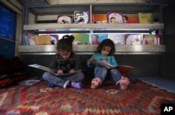Afghan children read books inside a library on wheels, in Kabul, Afghanistan, March 10, 2018.