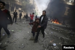 FILE - A man and girl rush from a site hit by airstrikes activists said were conducted by forces loyal to Syria's President Bashar al-Assad, in Douma, about 10 kilometers northeast of central Damascus, Nov. 7, 2015.